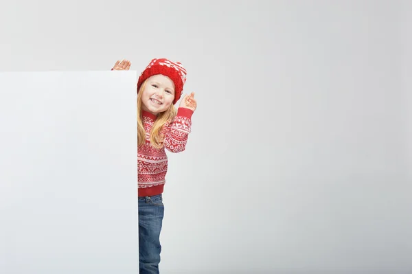 Sorrindo linda menina loira em um chapéu de inverno vermelho e suéter sagacidade — Fotografia de Stock