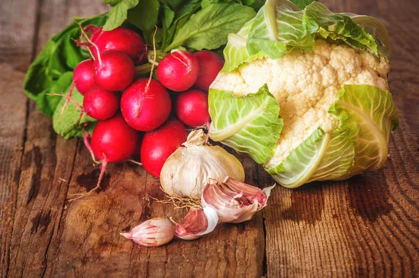 Radieschen und Blumenkohl in einer Papiertüte auf einem Holztisch — Stockfoto