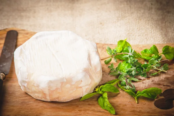 Вонючий голубой сыр на деревянном деревенском столе с ножом и базиликом — стоковое фото
