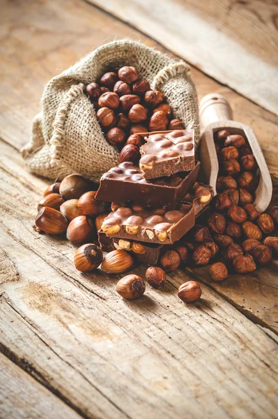 Chocolat au lait avec noisettes et noix dans un sac sur un bois — Photo