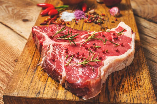 Close-up van vers vlees biefstuk met kruiden op houten achtergrond — Stockfoto