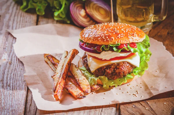 Delizioso un hamburger e patatine fritte con una birra sullo sfondo cipolla — Foto Stock