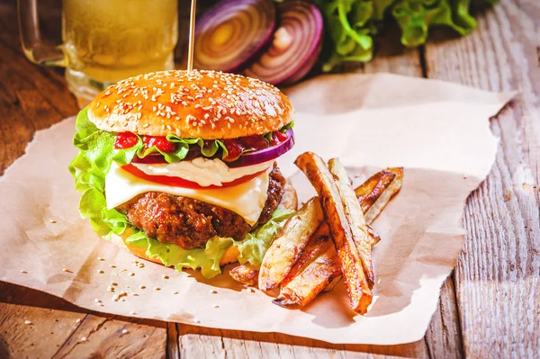 Lahodný hamburger a hranolky s pivem v pozadí cibule — Stock fotografie
