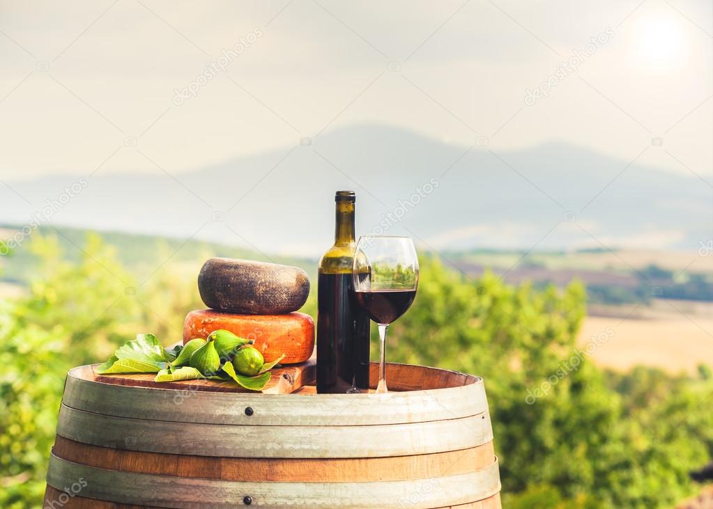 Red wine, cheese, figs on a wooden barrel in the background of t