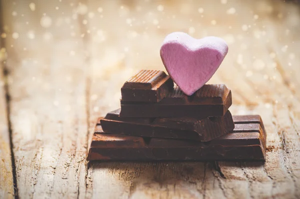 Vaaleanpunainen sydän musta suklaa maalaismainen puinen tausta — kuvapankkivalokuva