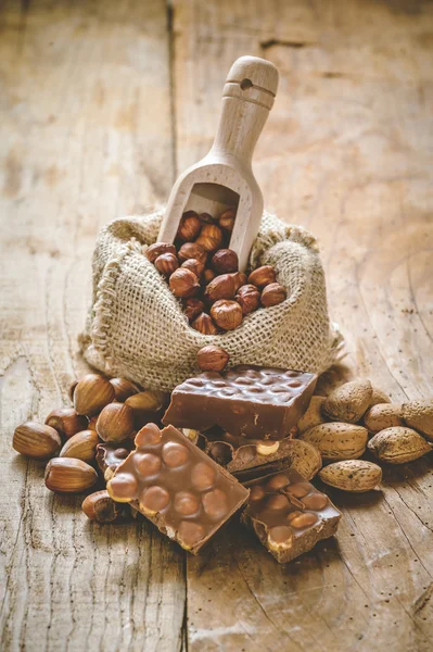 Chocolat au lait avec noisettes et noix dans un sac sur un bois — Photo