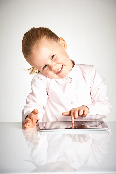 Söta lilla och leende flicka spelar med en tablett — Stockfoto