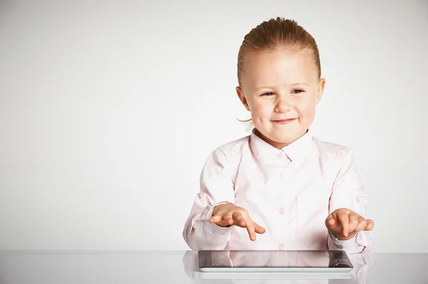 Cute little and smiling girl plays with a tablet — Stock Photo, Image