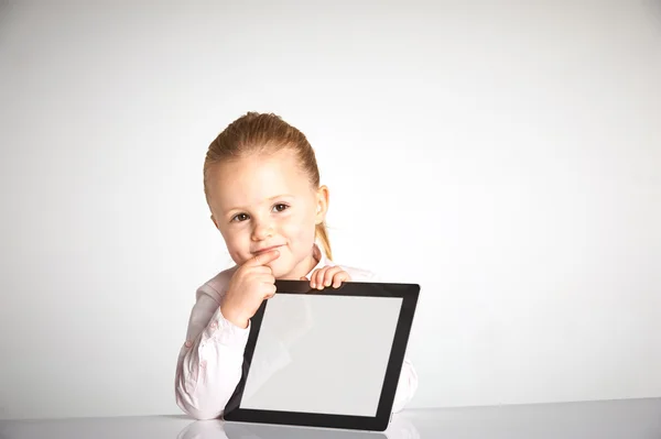 Menina bonito pouco e sorridente brinca com um tablet — Fotografia de Stock