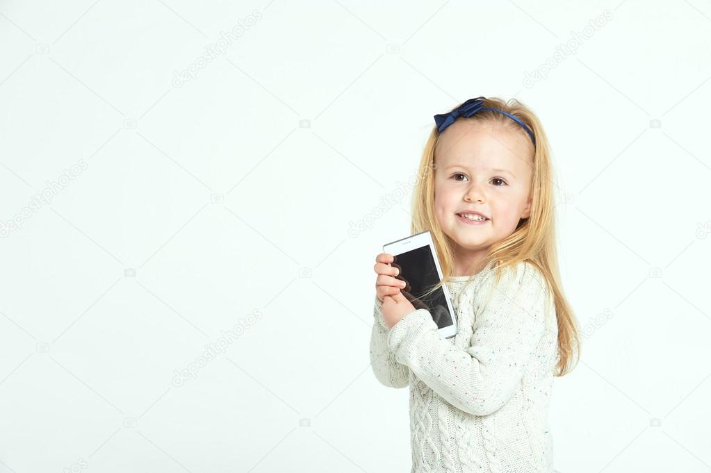 Cute little girl smiling and uses a smartphone, phone.