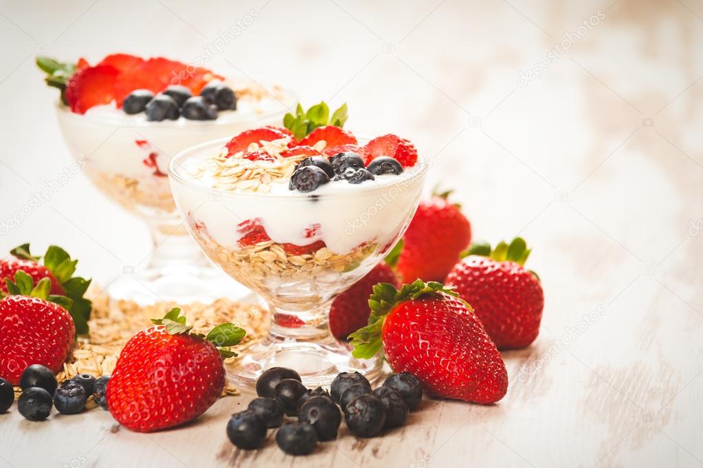 Strawberries, blueberries and breakfast cereal in yogurt on a wo