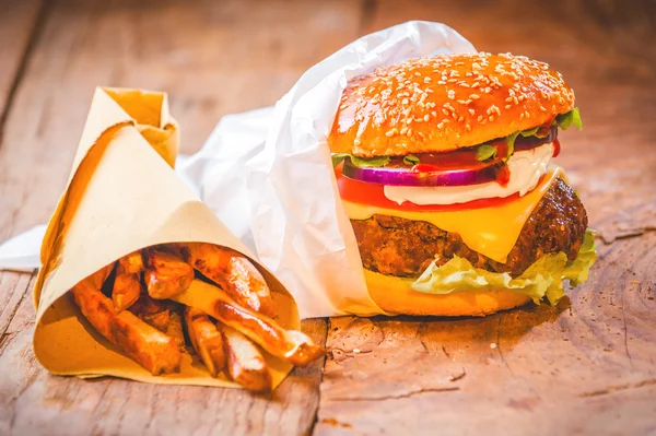 Delicious burger and chips, hand-made in the house on rustic tab Royalty Free Stock Photos