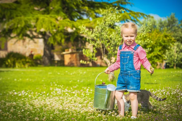 Little Girl and cat play on a green meadow in spring beautiful d — Stock Photo, Image