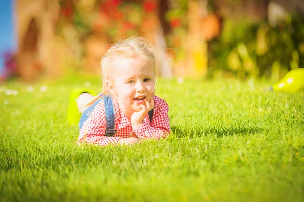 Maravilhosa menina brinca com na grama de primavera verde — Fotografia de Stock