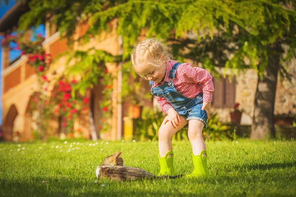 Little Girl and cat play on a green meadow in spring beautiful d — Stock Photo, Image