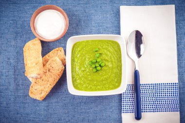 Green pea soup and bread on a blue tablecloth