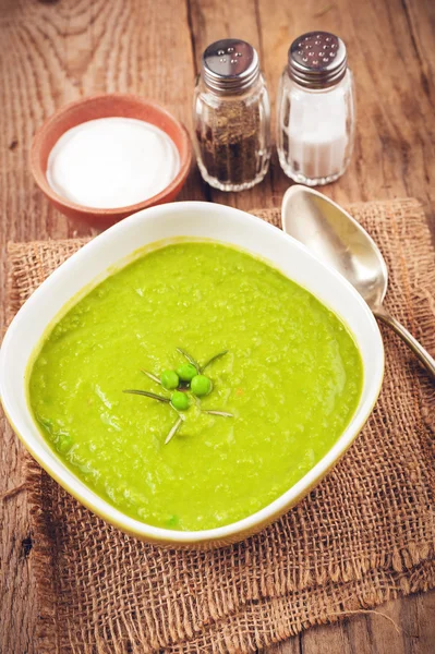 Green pea soup in a bowl with bread and sour cream on line table — Stockfoto