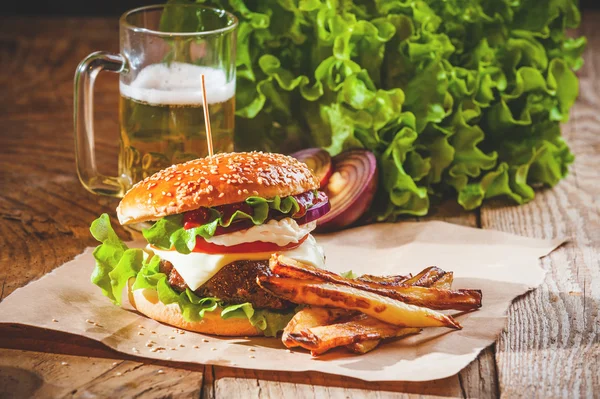 Delicious a burger and fries with a beer in the background onion — Stock Photo, Image