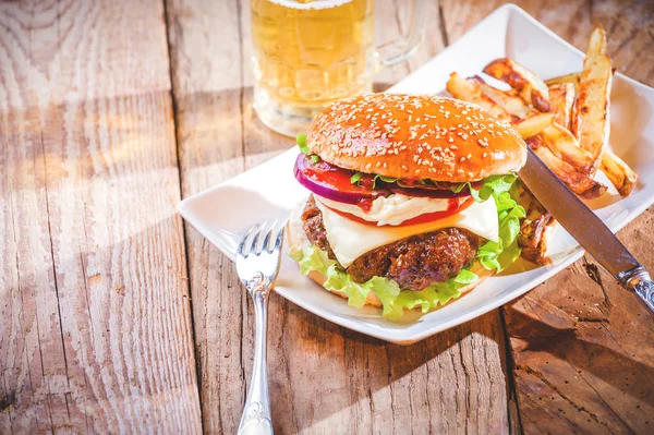 Delicious cheeseburger and french fries on a white plate on a wo — Stock Photo, Image