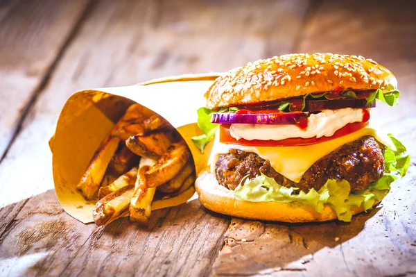 Delicious burger and chips, hand-made in the house on rustic tab Royalty Free Stock Images