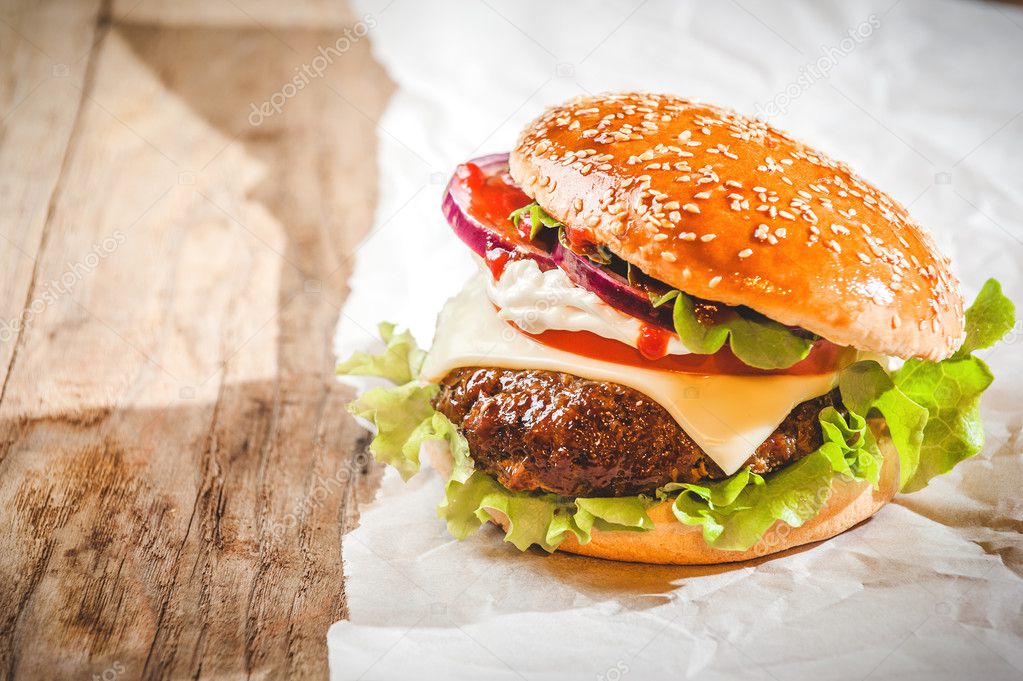 Tasty hamburger with fast food in a white paper on the wooden ta