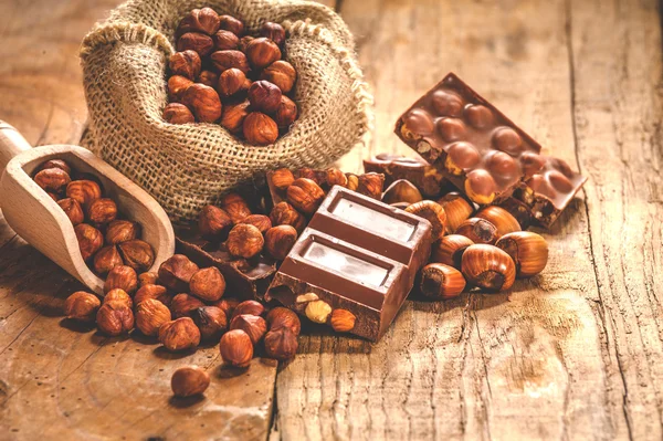 Melkchocolade met noten op een houten lepel in een landelijke stijl. — Stockfoto
