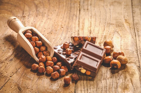 Melkchocolade met noten op een houten lepel in een landelijke stijl. — Stockfoto