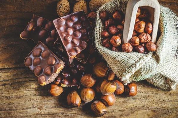 Chocolat au lait avec noisettes et noix dans un sac sur un bois — Photo