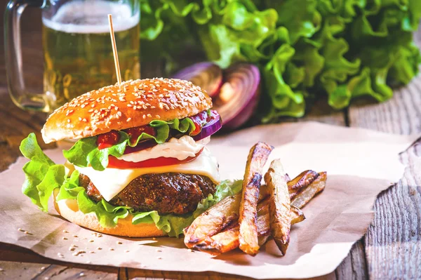 Delizioso un hamburger e patatine fritte con una birra sullo sfondo cipolla — Foto Stock