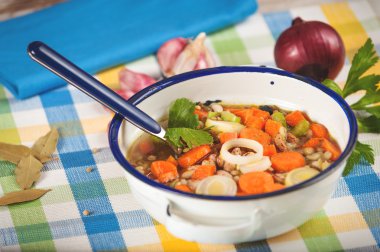 Kırsal bir rustik ahşap masa üzerinde metal bir kase sebze çorbası.