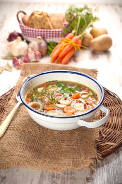 Kırsal bir rustik ahşap masa üzerinde metal bir kase sebze çorbası.