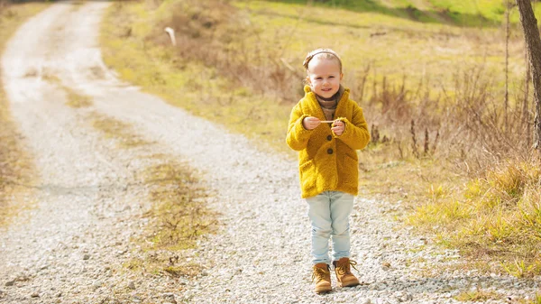 Niña sonriente en un camino de tierra en un día soleado . —  Fotos de Stock