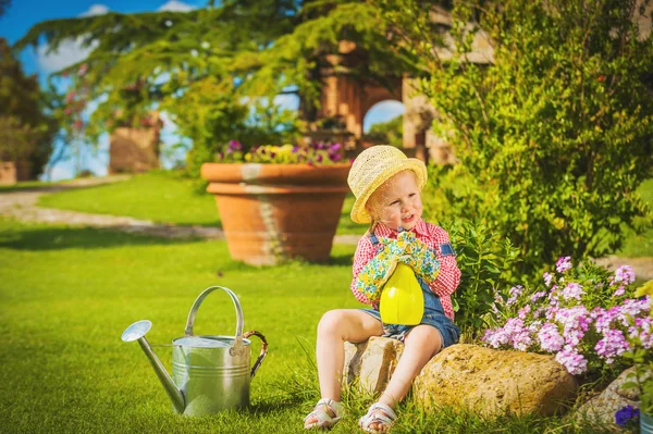 Roztomilá holčička dělat práci na zahradě mezi barevné květy. — Stock fotografie