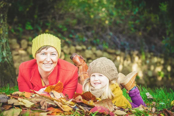 Beautiful mother and daughter playing in the park in autumn colo — Stock Photo, Image