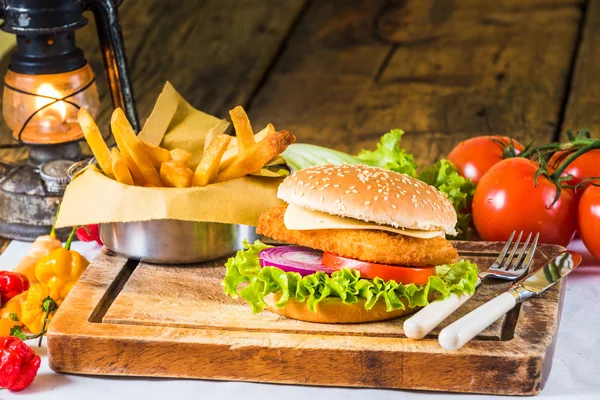 Plato de estilo rústico sobre una mesa de madera con una hamburguesa de pollo y f Fotos de stock