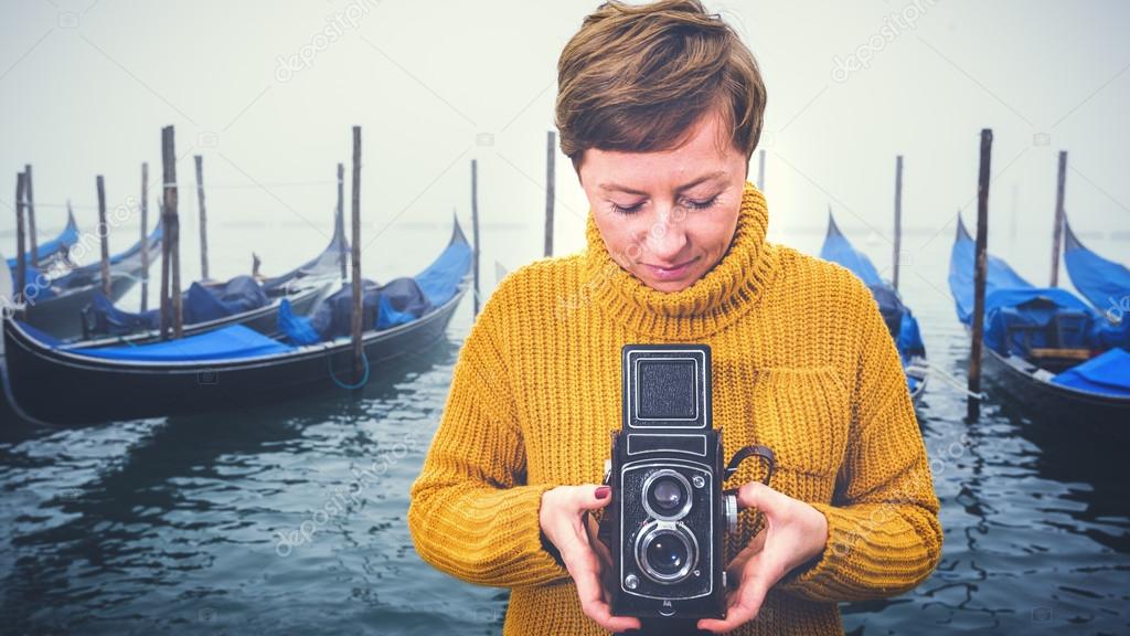 Beautiful young woman photographing gondolas in Venice, Italy