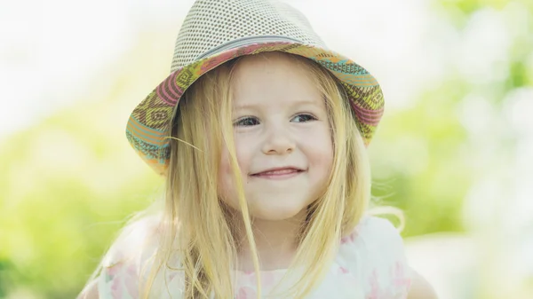 Sorrindo menina loira em um chapéu no dia ensolarado de verão no jardim . — Fotografia de Stock