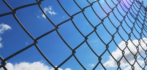 Beyaz bulutlar ve mavi gökyüzü arka plan ile dikenli tel çit