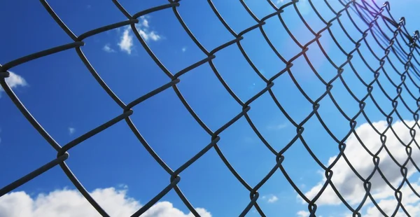 Beyaz bulutlar ve mavi gökyüzü arka plan ile dikenli tel çit