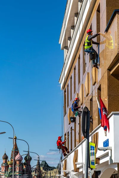 İşçiler Moskova 'nın tarihi merkezinin önündeki binanın ön cephesini temizliyorlar.
