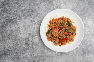 Gri beton masa üzerinde kutsal fesleğenle kızartılmış domuz eti..