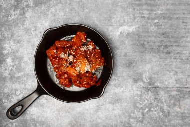 Tepede Kore soslu kızarmış tavuk gri beton masada beyaz susam..