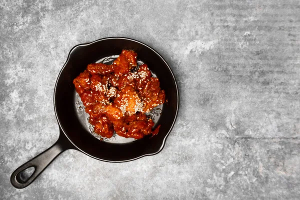 Tepede Kore soslu kızarmış tavuk gri beton masada beyaz susam..