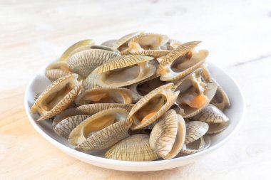 Beyaz bir tabakta pişmemiş istiridyeler..