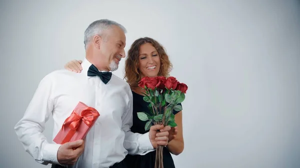 A happy elderly couple hugs and shares gifts and flowers at the celebration.