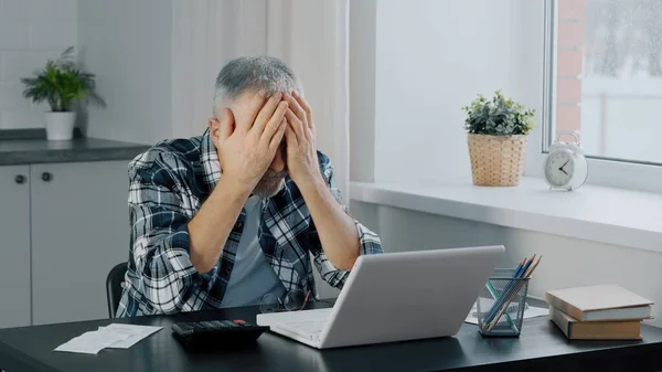 An elderly man keeps financial records at a computer.