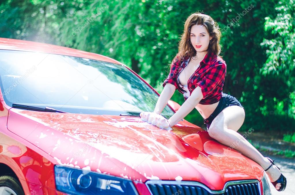 Hot brunette repairs a red car on the road in summer