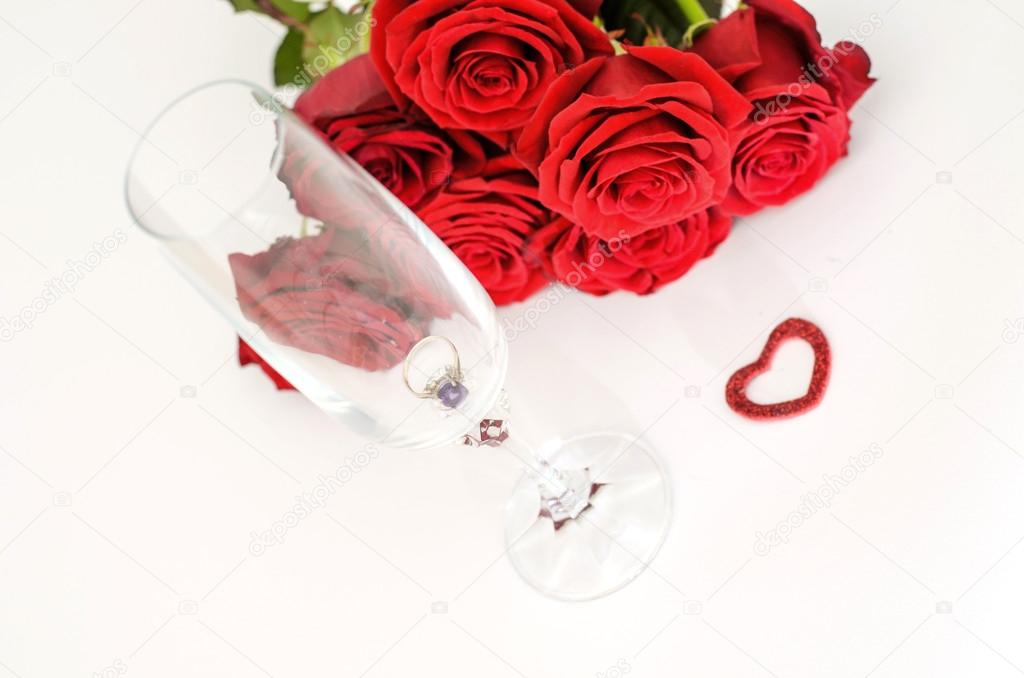 Red roses and a ring in a glass