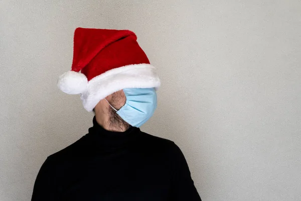 Man in blue face medical protective mask and santa Χριστουγεννιάτικο καπέλο, κρυμμένα μάτια. Royalty Free Φωτογραφίες Αρχείου