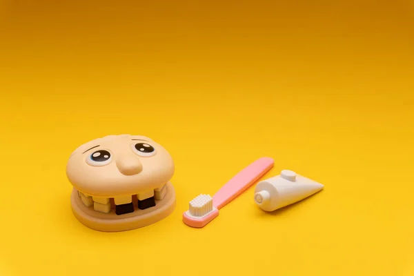 Οδοντιατρικά παιδιά παιχνίδι, σαγόνια, δόντια, οδοντόβουρτσα, οδοντόκρεμα, κίτρινο φόντο Royalty Free Εικόνες Αρχείου